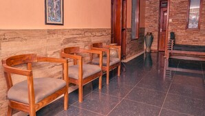 A hallway with wooden chairs, a stone wall, and a wooden door. - Sheron Hotel Kampala (Kampala)