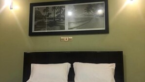 A neatly made bed with white linens in a room with green walls. - Sheron Hotel Kampala (Kampala)