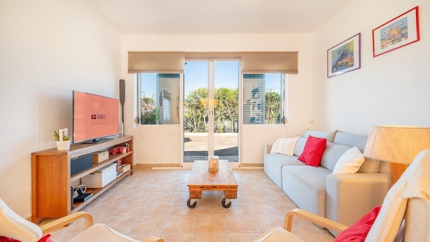 A modern living room with a sofa, chairs, a television, and a coffee table. - GuestReady - Peaceful vacation with pool (Setúbal)