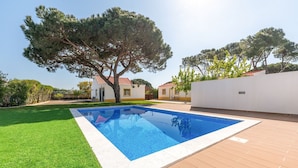 A rectangular swimming pool with a tiled edge, surrounded by a wooden deck and a well-maintained lawn. - GuestReady - Peaceful vacation with pool (Setúbal)