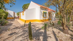 A white building with yellow trim and a red-tiled roof, surrounded by cacti and small trees. - GuestReady - Peaceful vacation with pool (Setúbal)