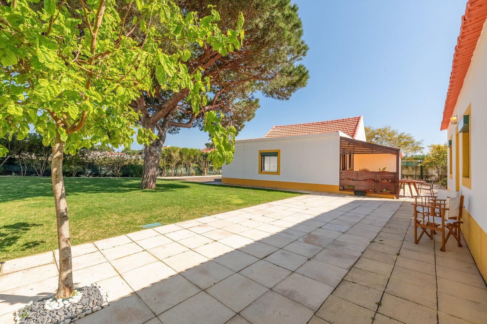 A patio area with a tiled floor, outdoor furniture, and a building with a red roof.