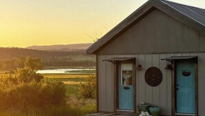 A small, single-story building with a sloped roof and a front porch. - Luxury in the country! The Dog- lovin’ Rockin' K offers A/C, WiFi and views! (Reed Point)