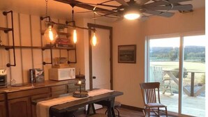 A kitchen with a central island, bar stools, a ceiling fan, and a view through a large sliding glass door. - Luxury in the country! The Dog- lovin’ Rockin' K offers A/C, WiFi and views! (Reed Point)