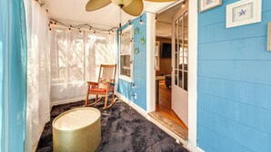 Una habitación con ventilador de techo, una mecedora, una cesta y una puerta que da a otra estancia.