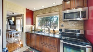 Una cocina moderna con armarios de madera, un microondas de acero inoxidable y un horno empotrado.