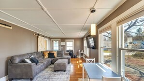 Una sala de estar moderna con un sofá seccional, una mesa de comedor y ventanas amplias que ofrecen vistas al exterior.