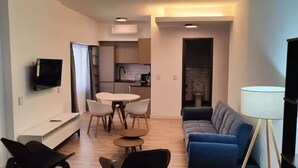 A modern living room with a sofa, a TV, a dining table with chairs, and a kitchen area in the background. - Berni Rentals Ciudad Vieja (Montevideo)