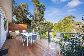 A wooden deck with outdoor furniture, a dining table, and chairs. - Fair Waves (Lorne)