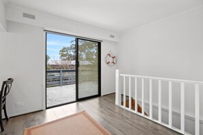 Habitació amb porta corredissa de vidre que dona a zona exterior, barana blanca i un salvavides penjat a la paret.