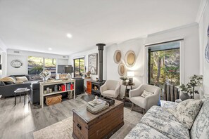 A modern living room with a fireplace, comfortable seating, and a bookshelf. - Fair Waves (Lorne)