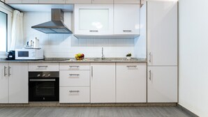 Une cuisine moderne avec des armoires blanches, un four encastré, un four à micro-ondes et une hotte de cuisinière en acier inoxydable.