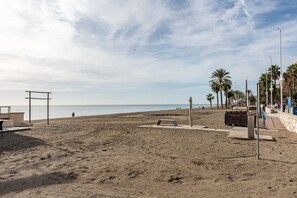 Una playa con arena, algunas personas y palmeras.