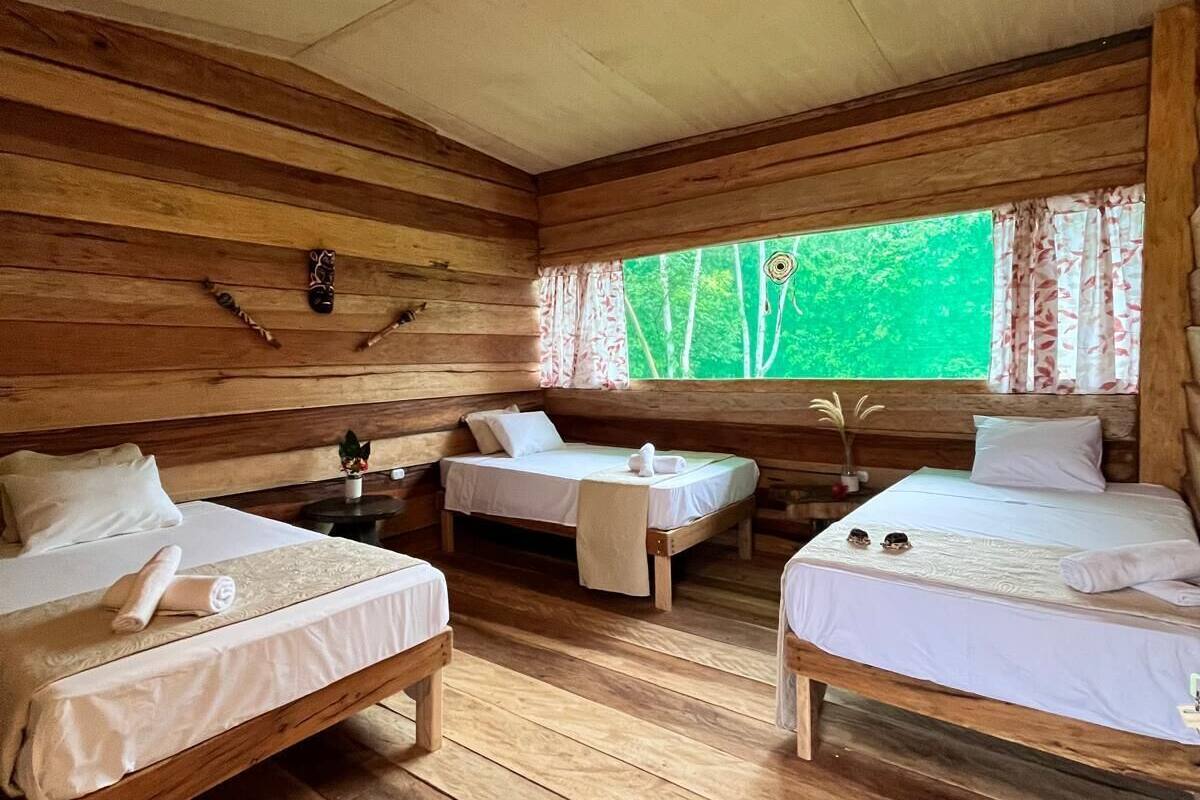 A cabin with two wooden beds, a small table, and a window with curtains.
