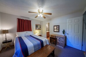 A bedroom with a bed, a desk, a chair, a ceiling fan, a door, and a window with curtains. - Dock To Do Little lakefront w/boat slip & firepit (Scottsboro)