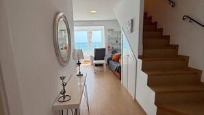 Un intérieur moderne avec un escalier, une vue sur l’extérieur et une petite table avec une lampe.