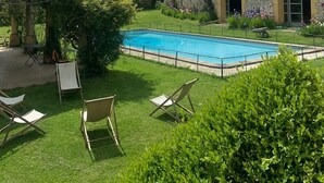 A courtyard with a swimming pool, lounge chairs, and a historic building with a bell tower in the background.