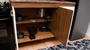 Une cuisine dotée d’une étagère intégrée sous le plan de travail, où sont rangés divers ustensiles de cuisine.