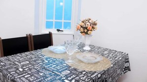 Une table à manger recouverte d’une nappe à motifs noir et blanc, un vase rempli de fleurs et de la verrerie transparente.