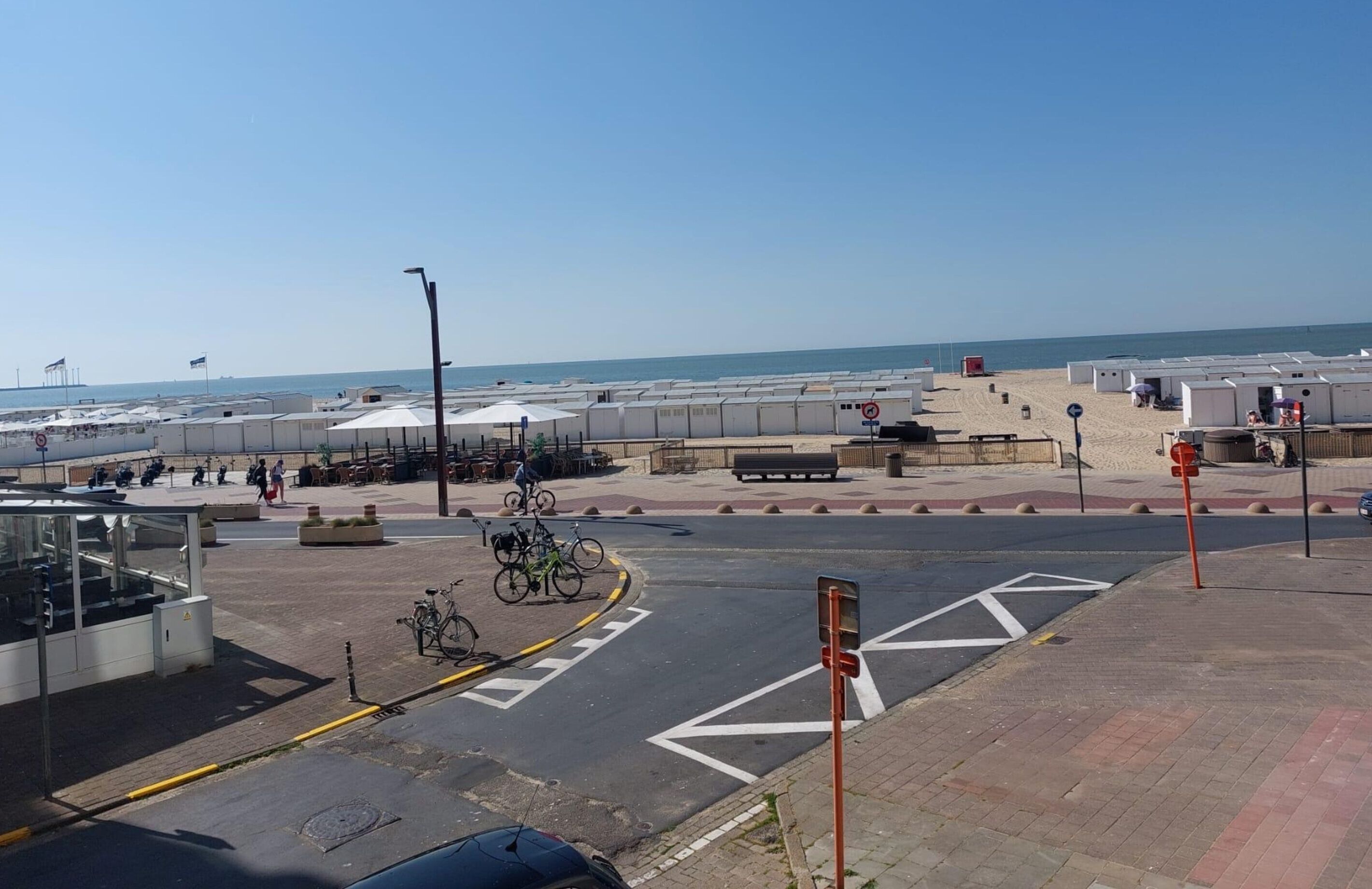 A beachside area with a road, bicycles, and beach umbrellas.