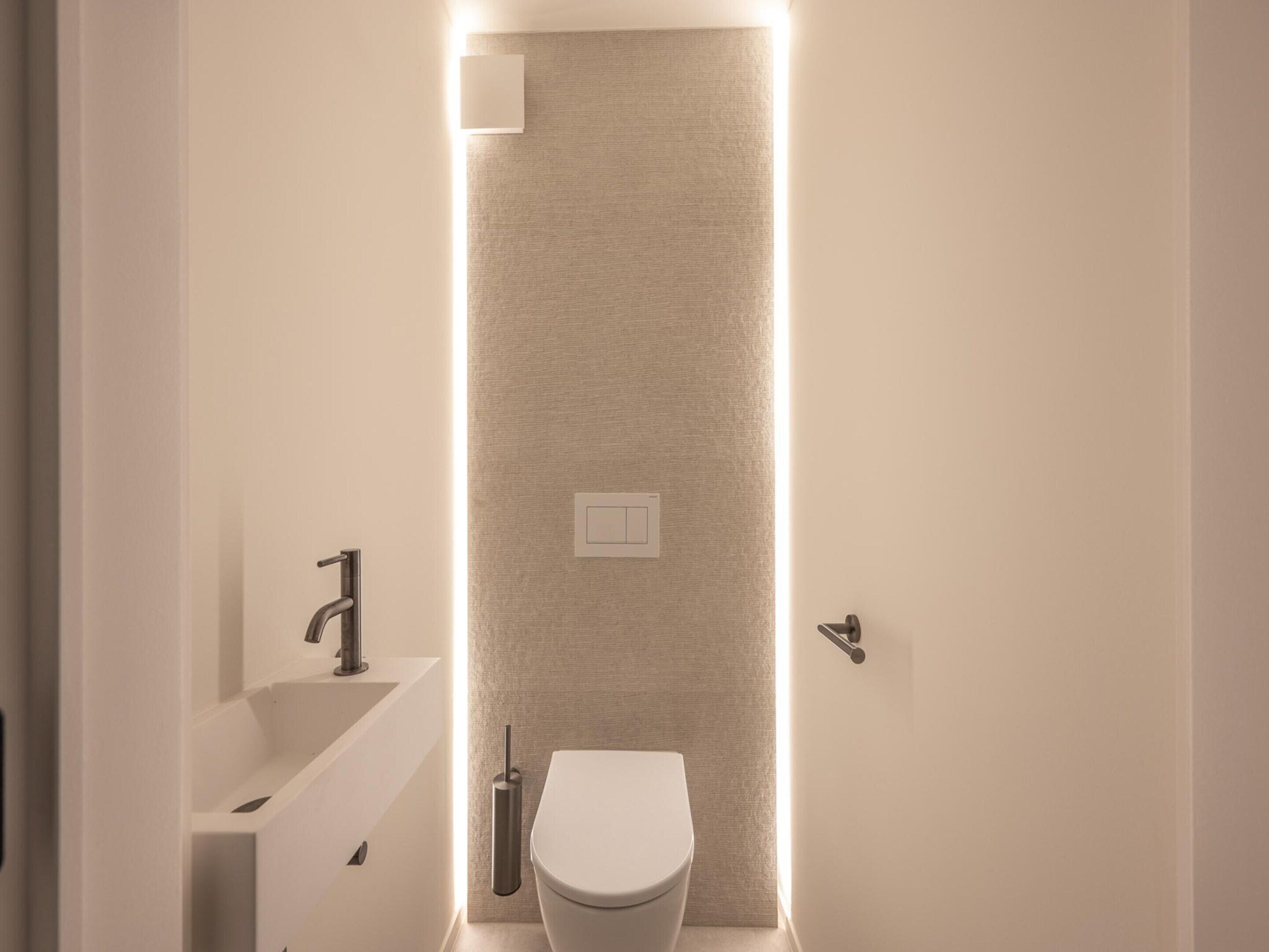 A modern bathroom with a toilet, a sink, and a shower area.
