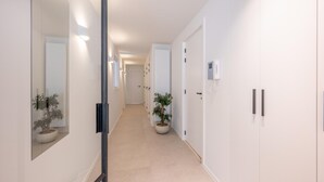 Un couloir avec un mur recouvert de miroirs, une plante en pot et une porte sur laquelle est fixé un téléphone.