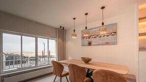 Un espace repas moderne avec une grande fenêtre, une table en bois et trois chaises.
