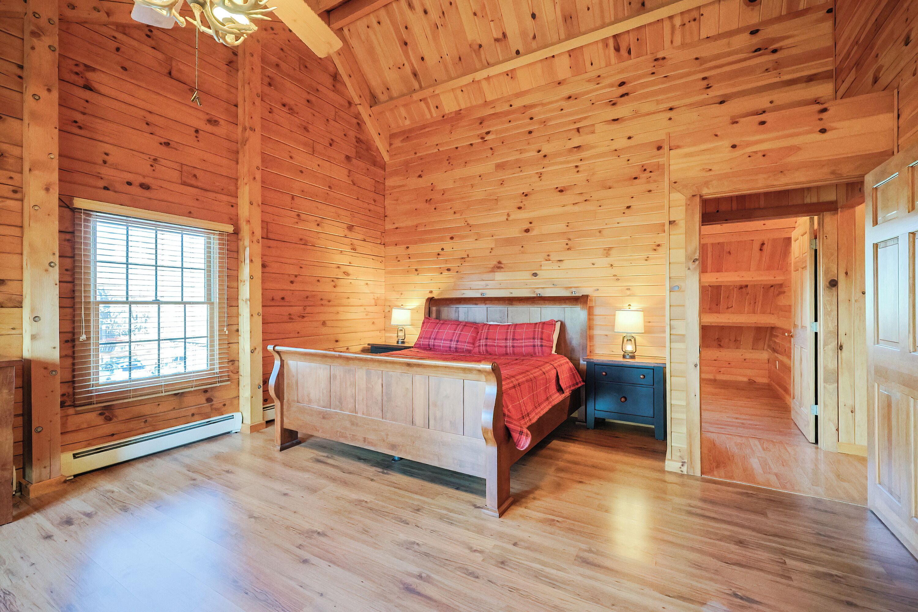 A wooden cabin bedroom with a bed, bedside tables, and a window.