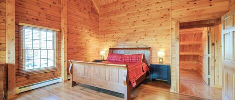 A wooden cabin bedroom with a bed, bedside tables, and a window.