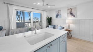 Een moderne keuken met een groot eiland, witte kasten en uitzicht op de omgeving.