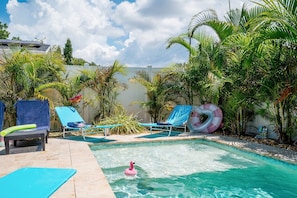 A swimming pool with lounge chairs and a flamingo float.