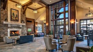 A spacious lobby with a fireplace, comfortable seating, and large windows offering views. - 4th of July in Breckenridge at Grand Lodge on Peak 7 (Breckenridge)
