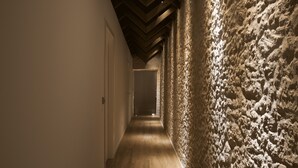 Un couloir doté d’un plancher en bois et d’un mur à texture sur l’un de ses côtés.