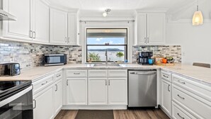 A modern kitchen with white cabinetry, a large window with a view, a coffee maker, and a toaster. - Lakefront Oasis- Steps to Water- Private Boat Ramp (Dandridge)