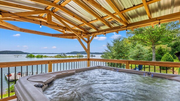 A hot tub under a wooden pergola with a view of a lake and trees. - Lakefront Oasis- Steps to Water- Private Boat Ramp (Dandridge)