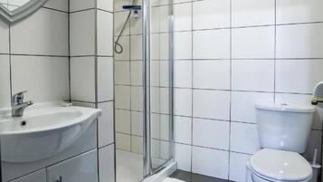 A modern bathroom with a white sink, mirror, and toilet.