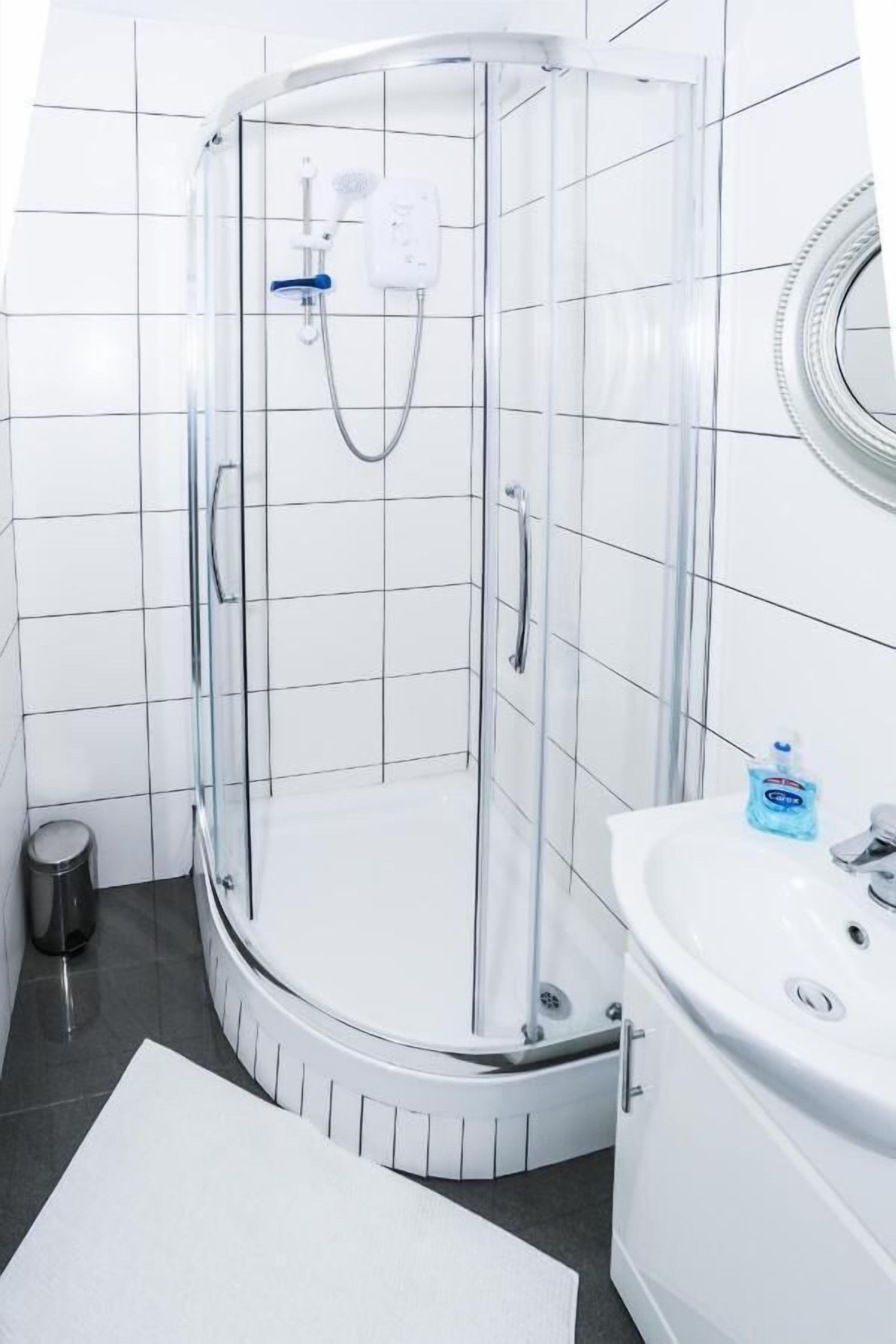 Un baño moderno con ducha de vidrio, lavamanos blanco y espejo.