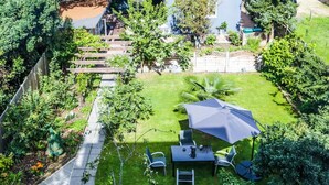 A well-maintained garden with a patio area, including a table and chairs, surrounded by various plants and a wooden fence. - Beckenham Park Hotel (Beckenham)