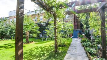 A garden with a pergola, a pathway, and various plants.