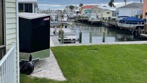 A marina with boats docked, a grassy area, and a building with a porch.
