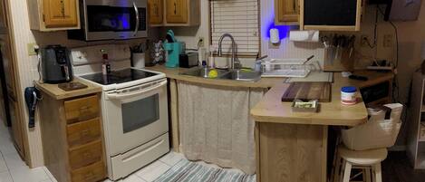 A compact kitchen with wooden cabinets, a built-in microwave, a stove, and a sink.