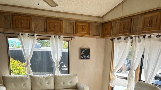 A living room with a sectional sofa, a recliner, and a ceiling fan.