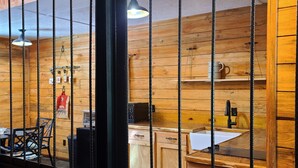 A rustic wooden interior with a kitchen area, including a sink, cabinets, and a coffee machine. - Hidden in East Texas Piney Woods - Rustic Western Cabin - Canton 1st Monday (Mineola)