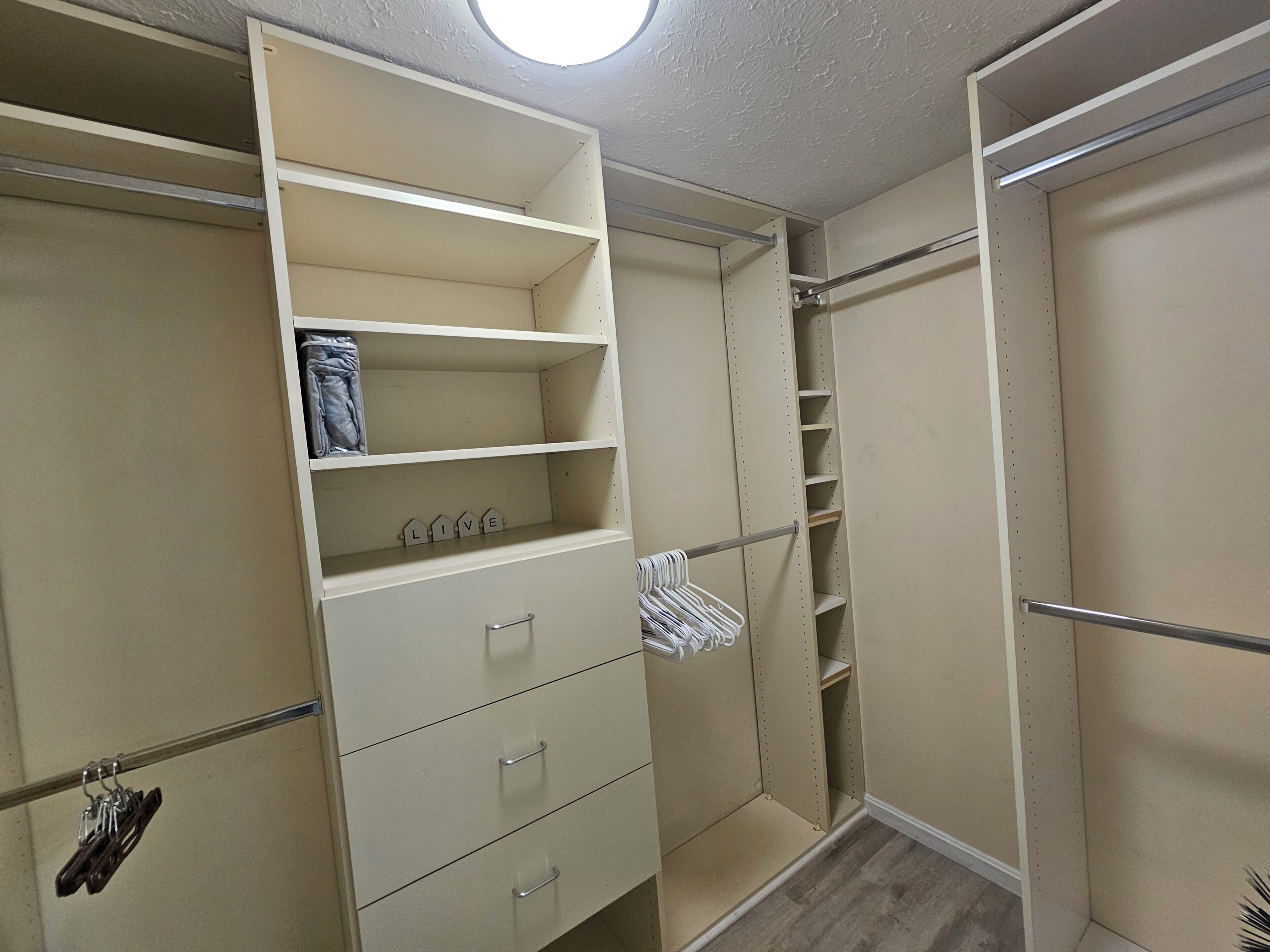 A walk-in closet with open shelves, hanging space, and a full-length mirror.