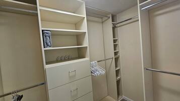 A walk-in closet with open shelves, hanging space, and a full-length mirror.