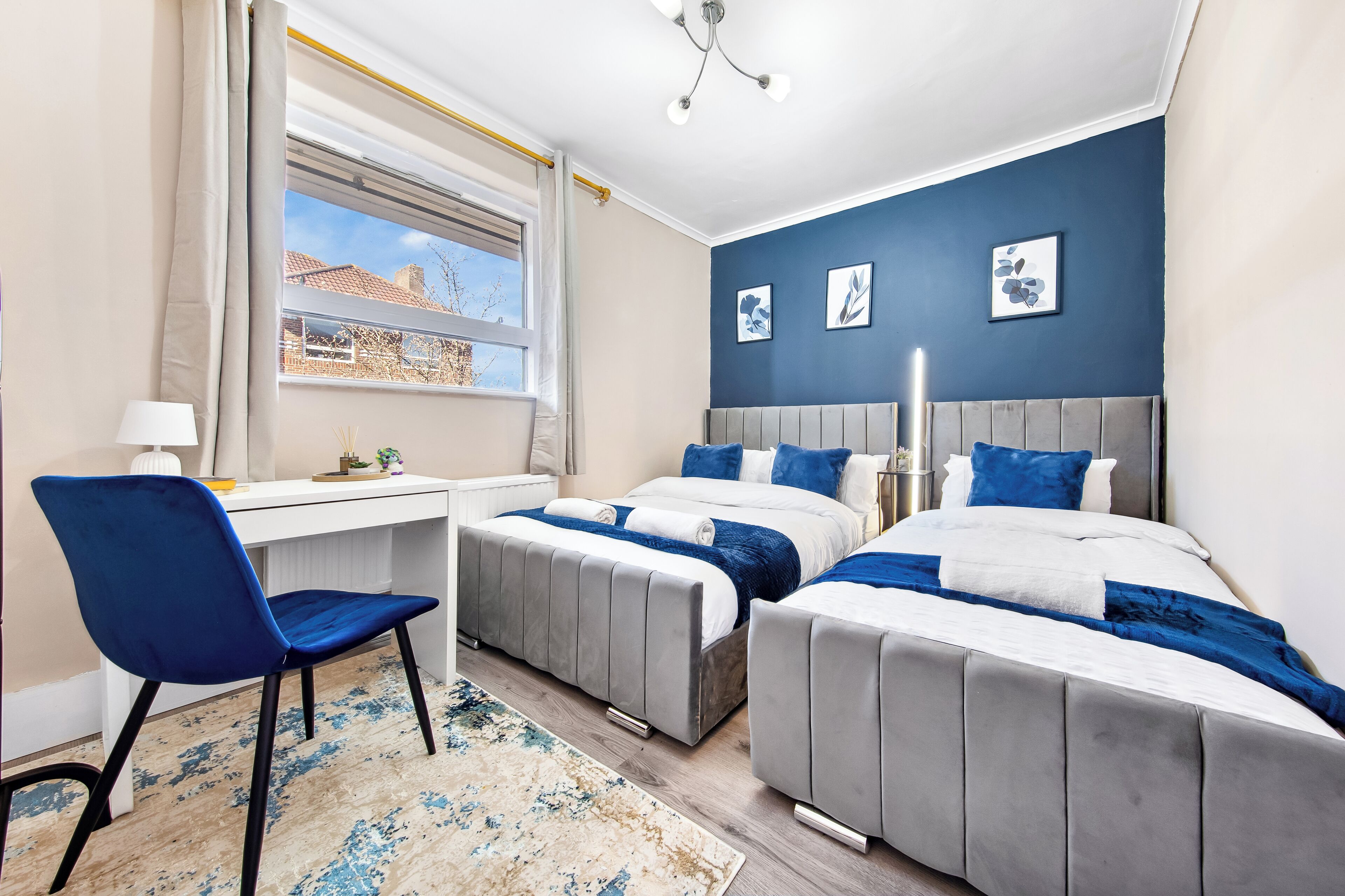 A bedroom with two beds, a desk, and a chair.