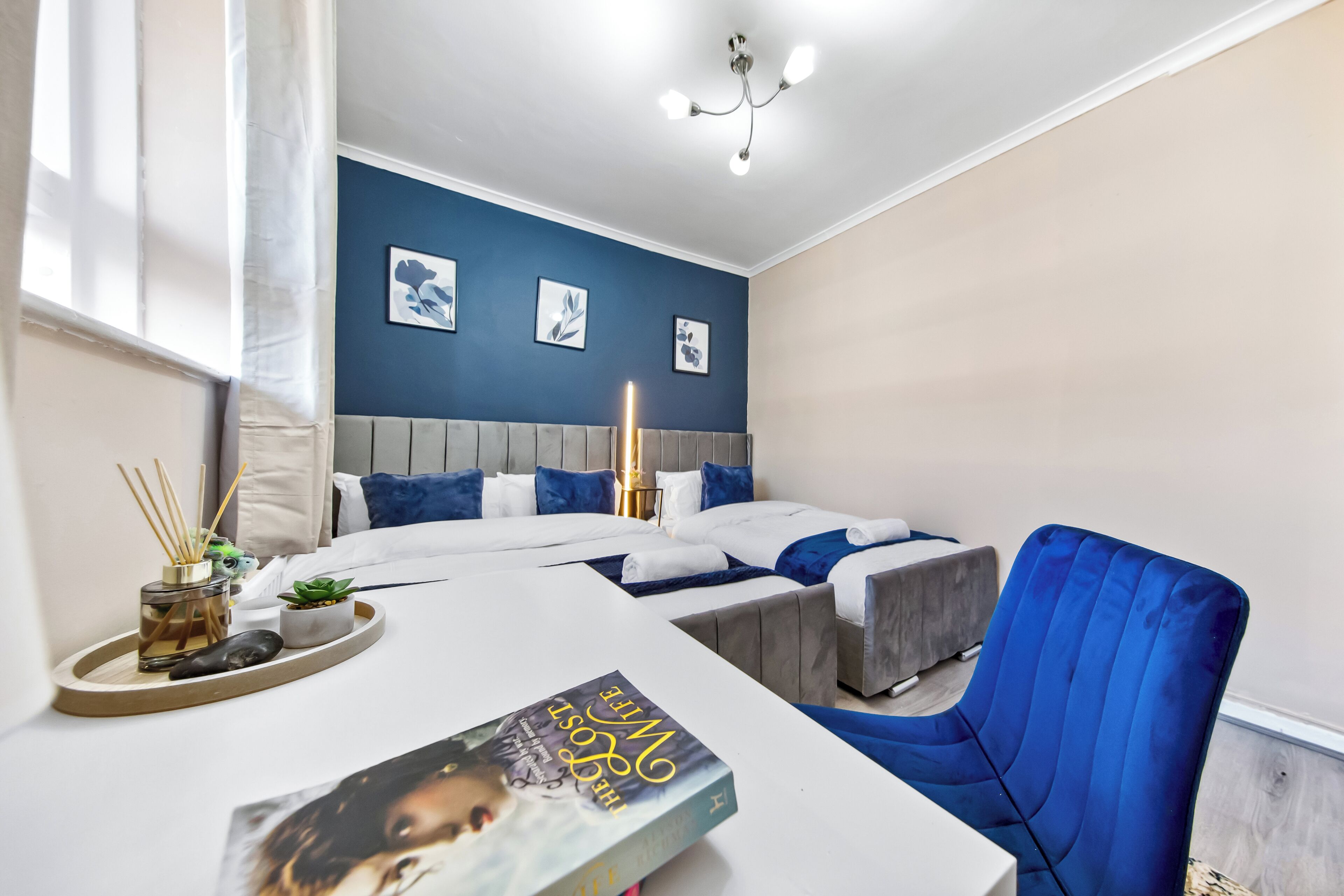 Un dormitorio moderno con una cama, mesitas de noche y una silla azul.