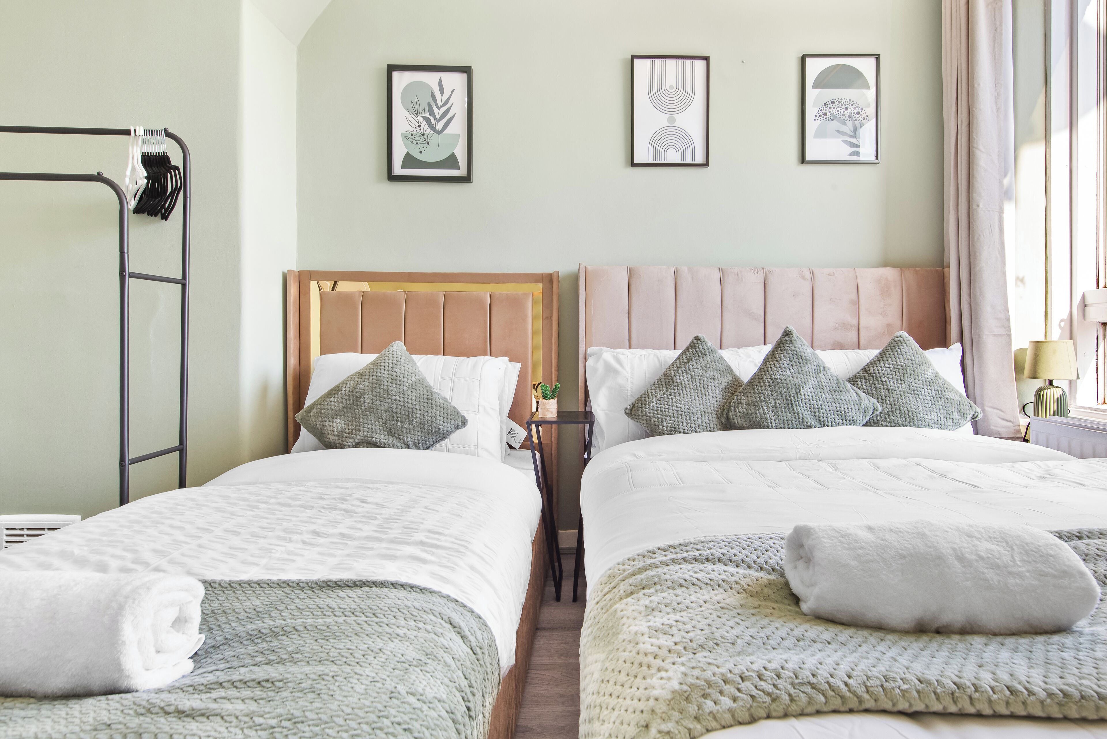Une chambre double avec deux lits, une armoire en métal et des œuvres d’art encadrées accrochées au mur.