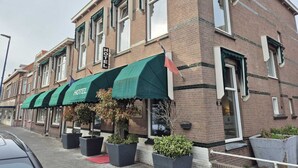 Un hotel con toldo verde, fachada de ladrillo y varias ventanas.