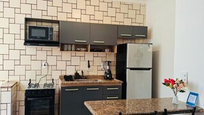 Une cuisine compacte équipée d’un four à micro-ondes, d’une cuisinière, d’un réfrigérateur et d’un plan de travail en granit.